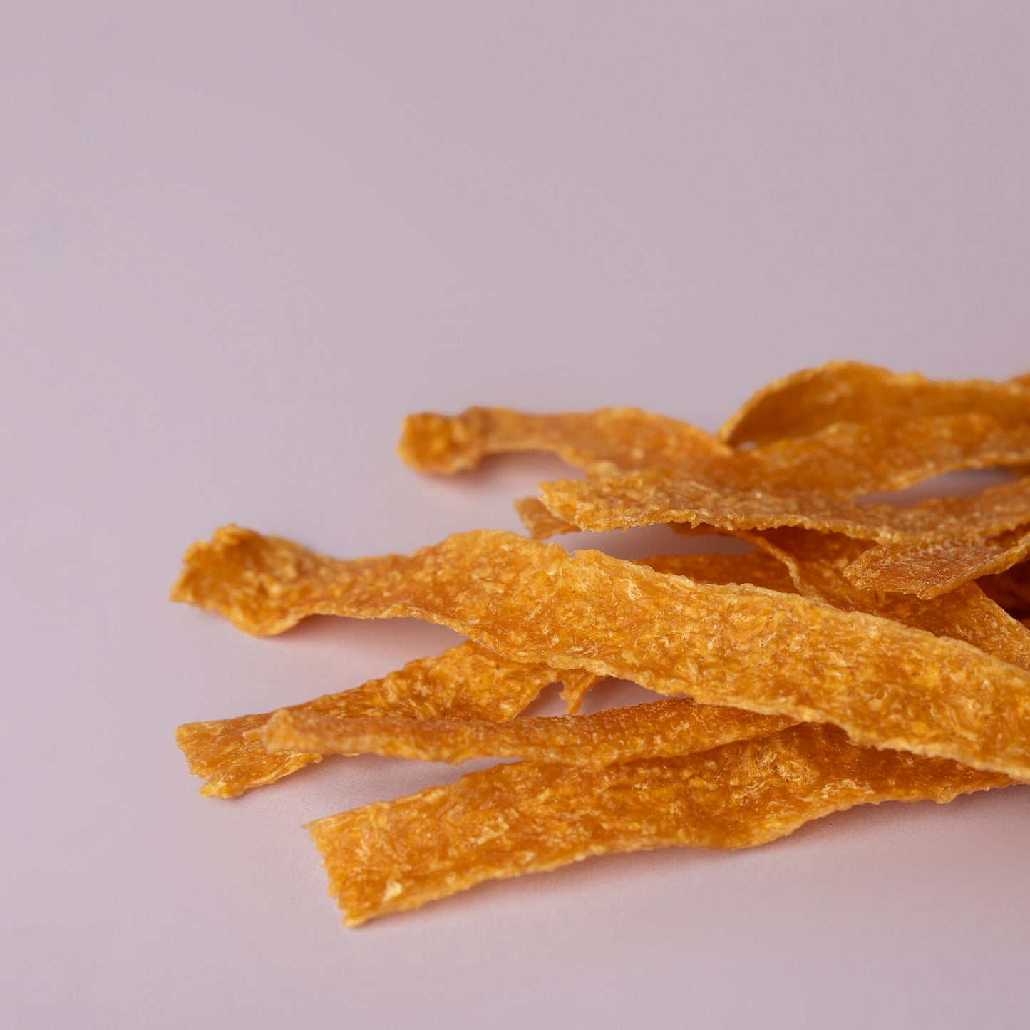 locally made chicken jerky strips, single ingredient dog treat; chicken strip on purple background