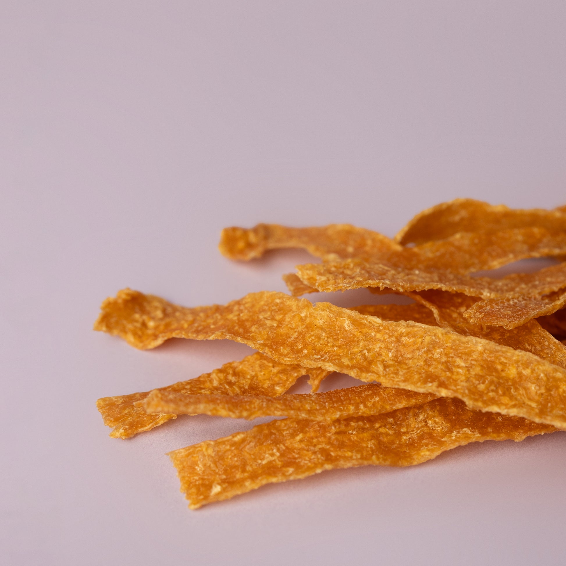 locally made chicken jerky strips, single ingredient dog treat; chicken strip on purple background