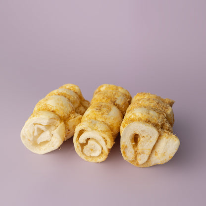 A bundle of rolled beef cheek dog chews, dusted with bully stick powder, against a purple background, rawhide alternative for dogs, beef cheek roll for dogs